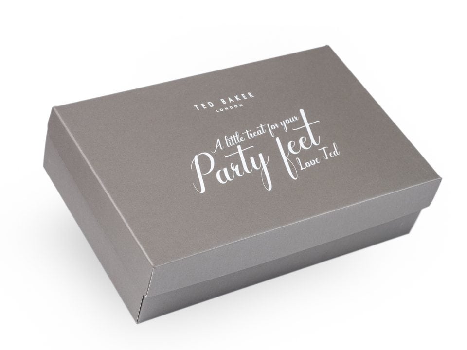 A sleek gray gift box by TED BAKER adorned with the charming text "A little treat for your party feet. Love Ted" in elegant white script.