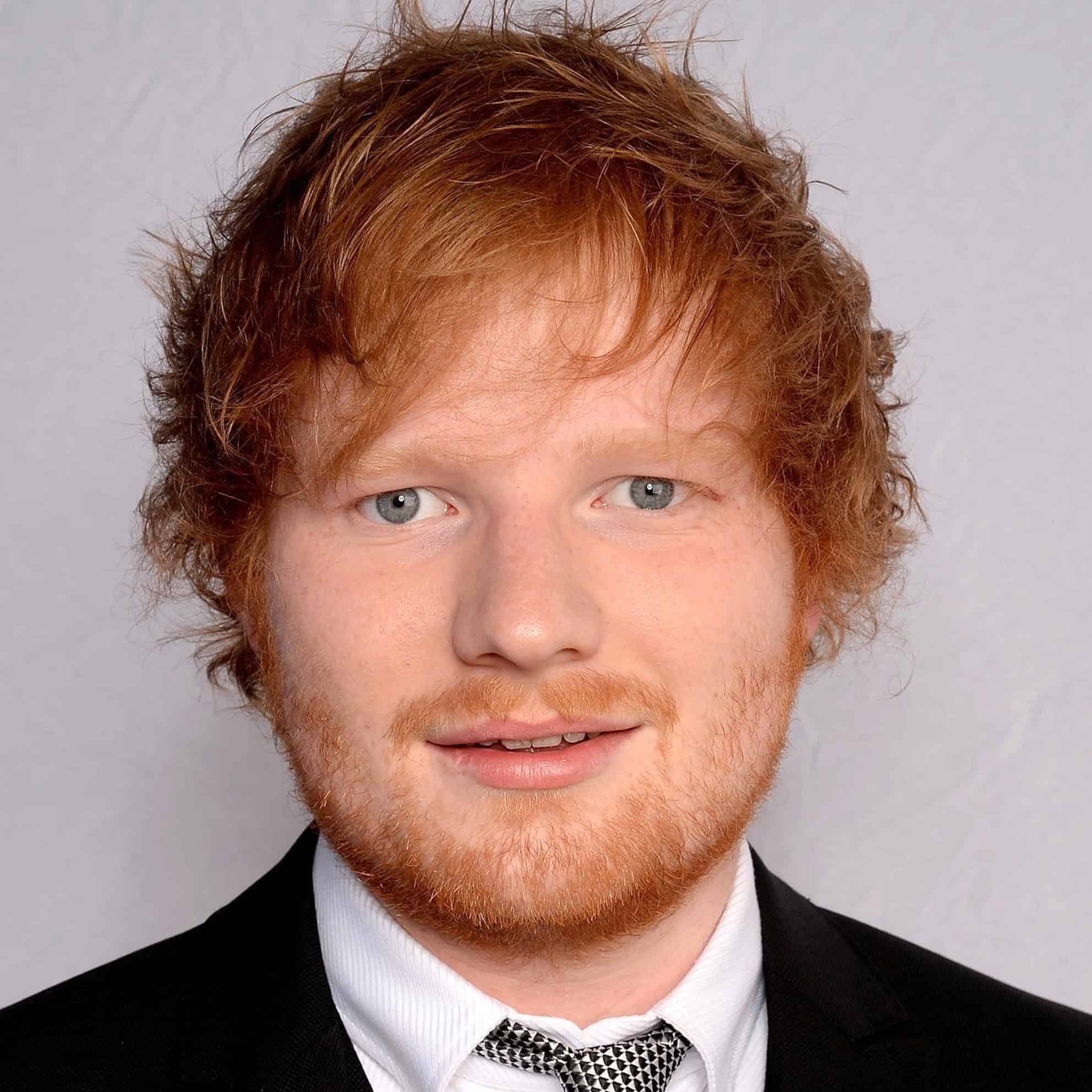 A person with curly red hair and a beard, representing The Print 4 Team, smiles confidently at the camera in a suit and tie against a plain background.