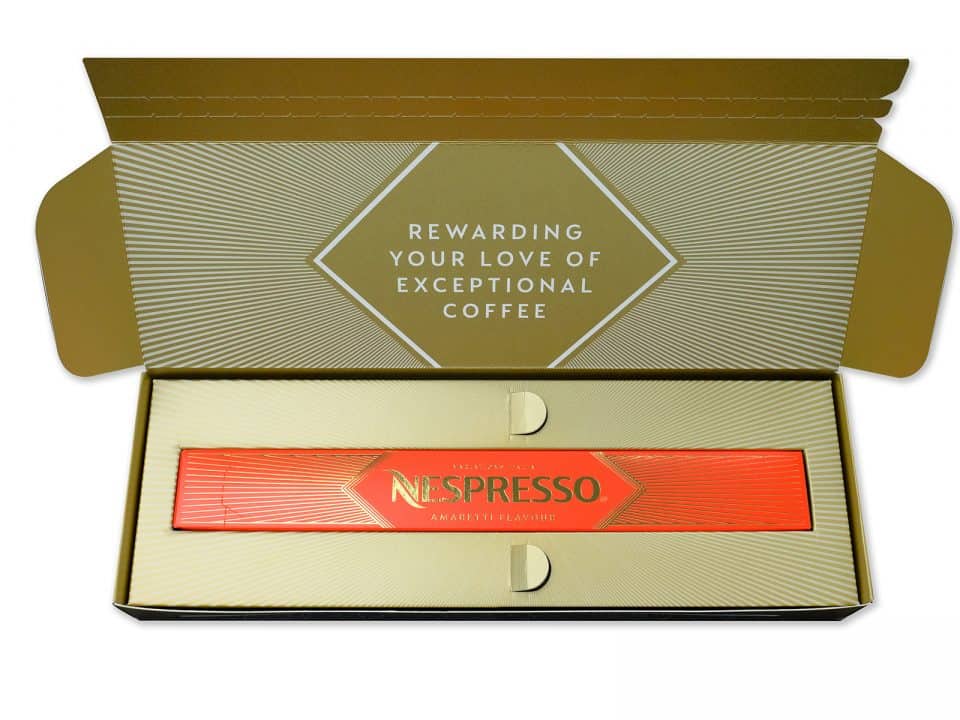 Inside an elegant open package, this Nespresso box showcases amaretto flavor capsules with a sophisticated gold and cream design, making it a perfect choice for a memorable gift box experience.